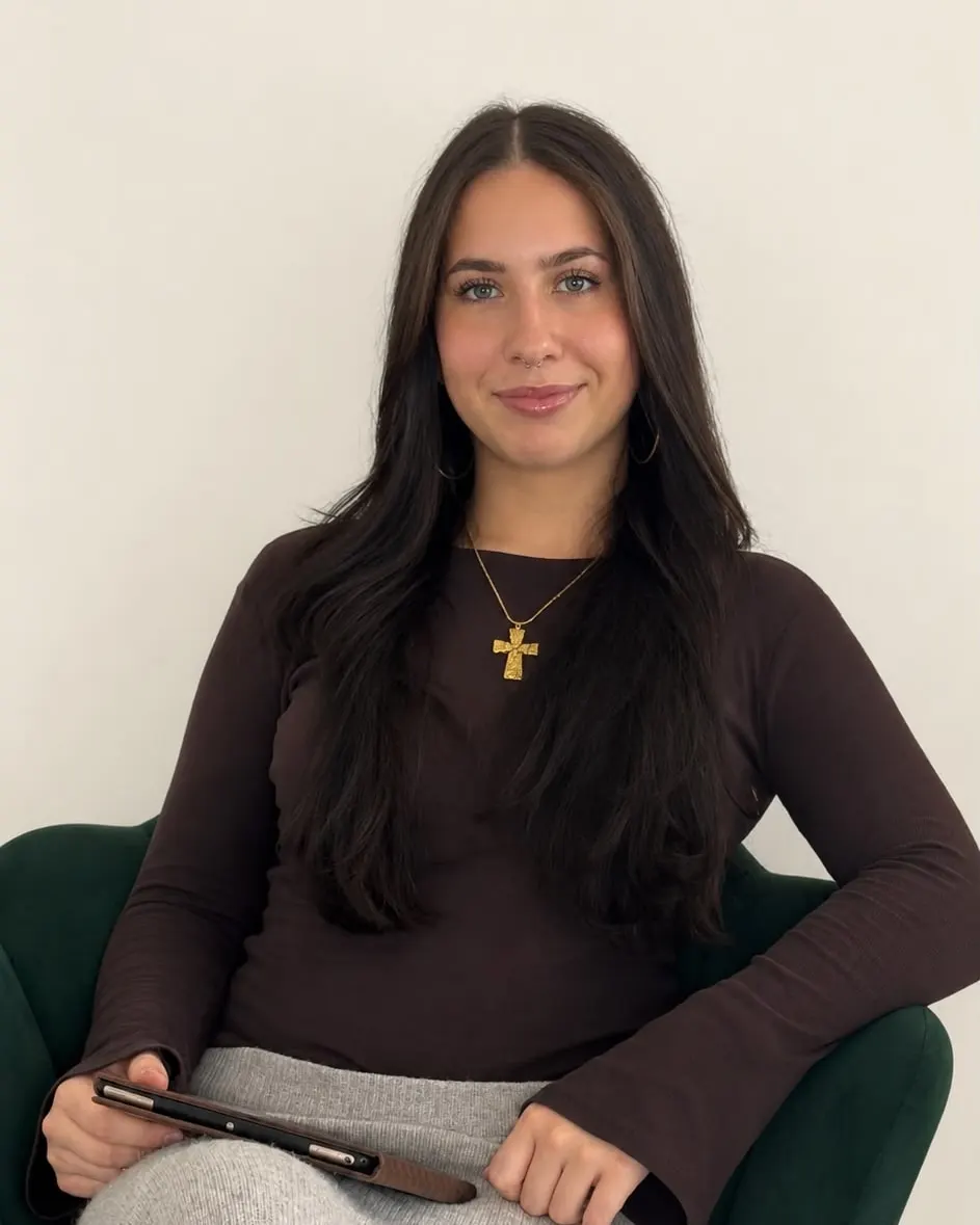 Bella, founder of Sinclair Socials, sitting in a green armchair